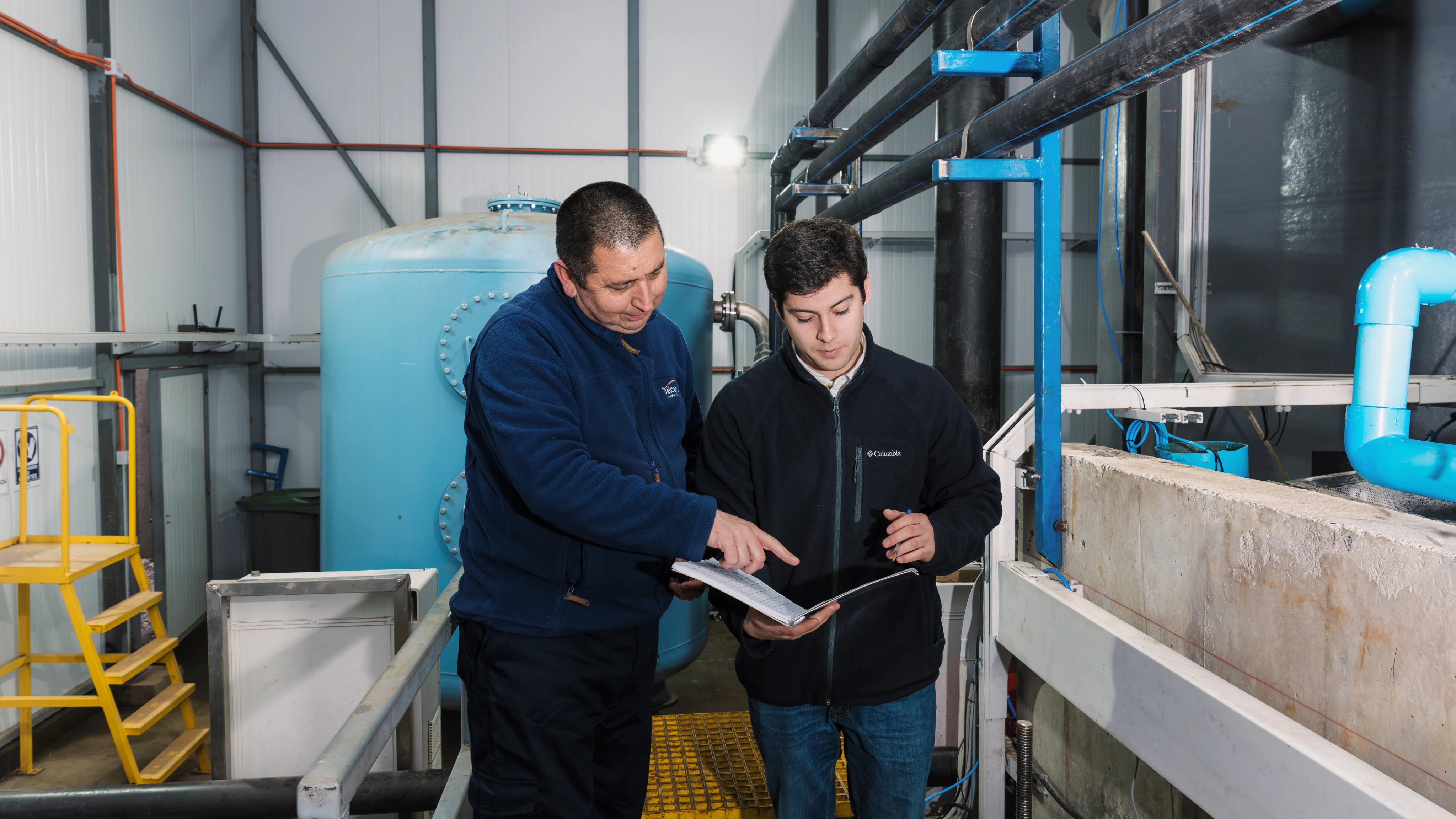 Technical team reviewing documentation in front of rearing tanks